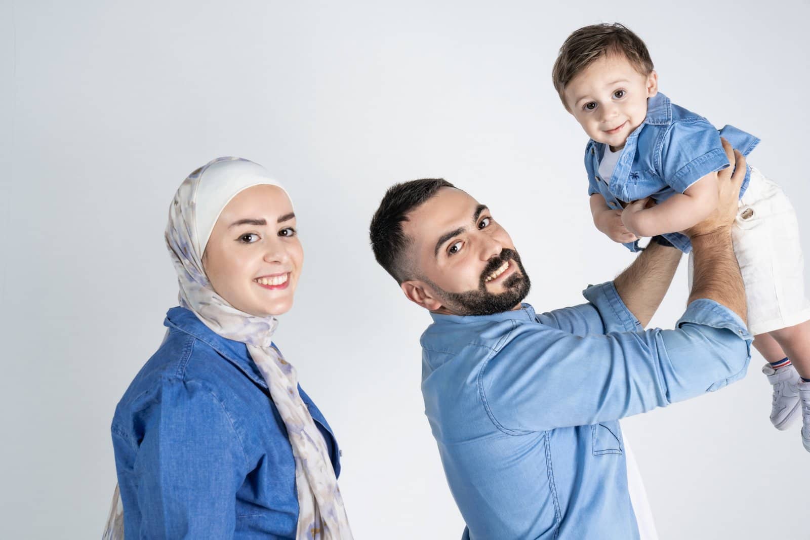 Parents and toddler laughing on white
