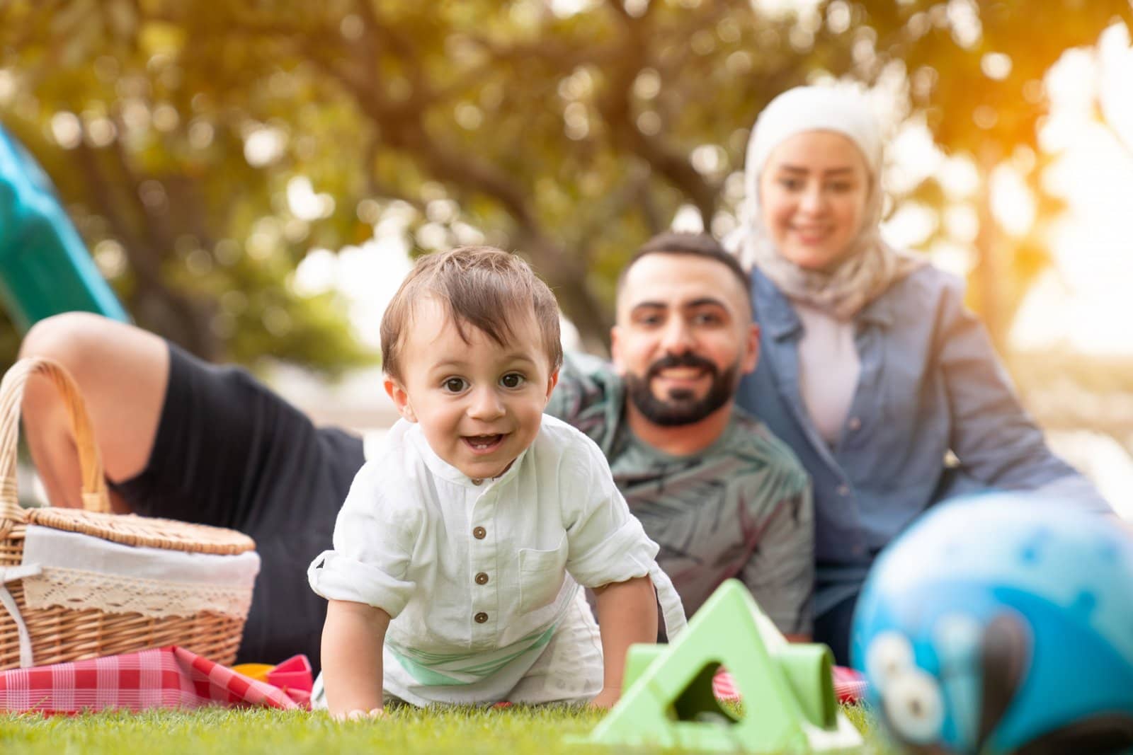 Toddler crawling on grass with family behind