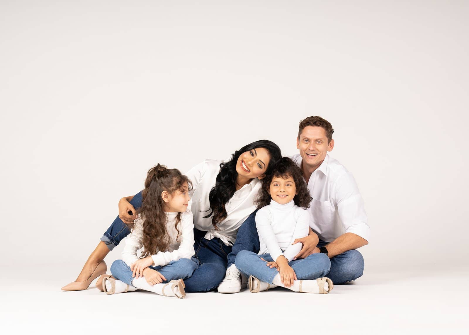 Family seated together on a white floor