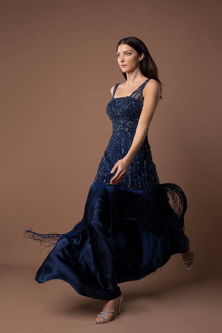 Model in a navy sequinned gown on a warm backdrop