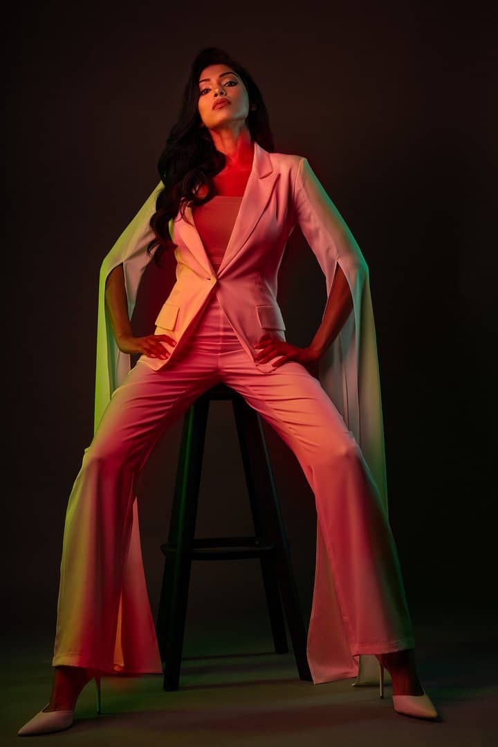 Model in a coral suit under split colour lighting