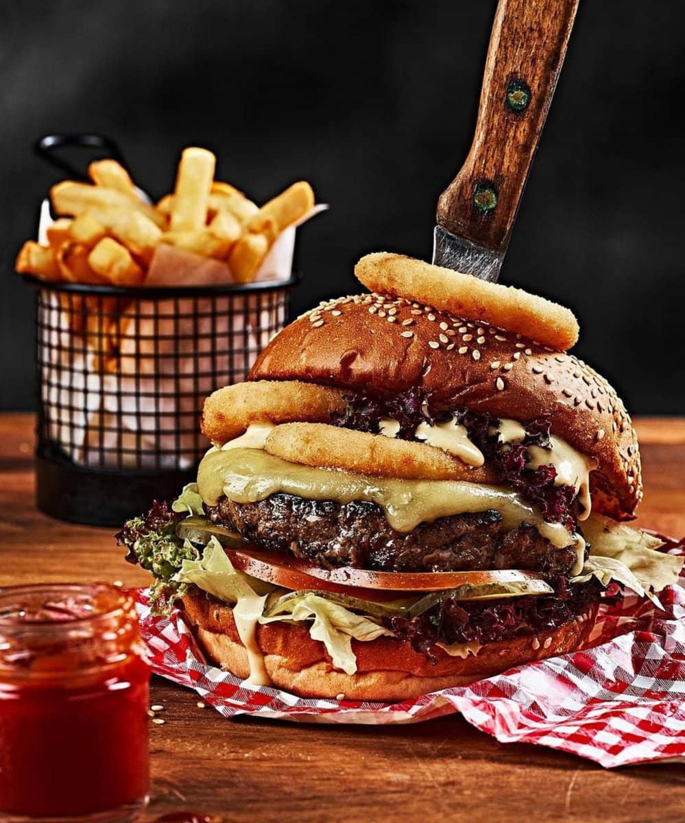 Stacked burger and fries on a checked cloth