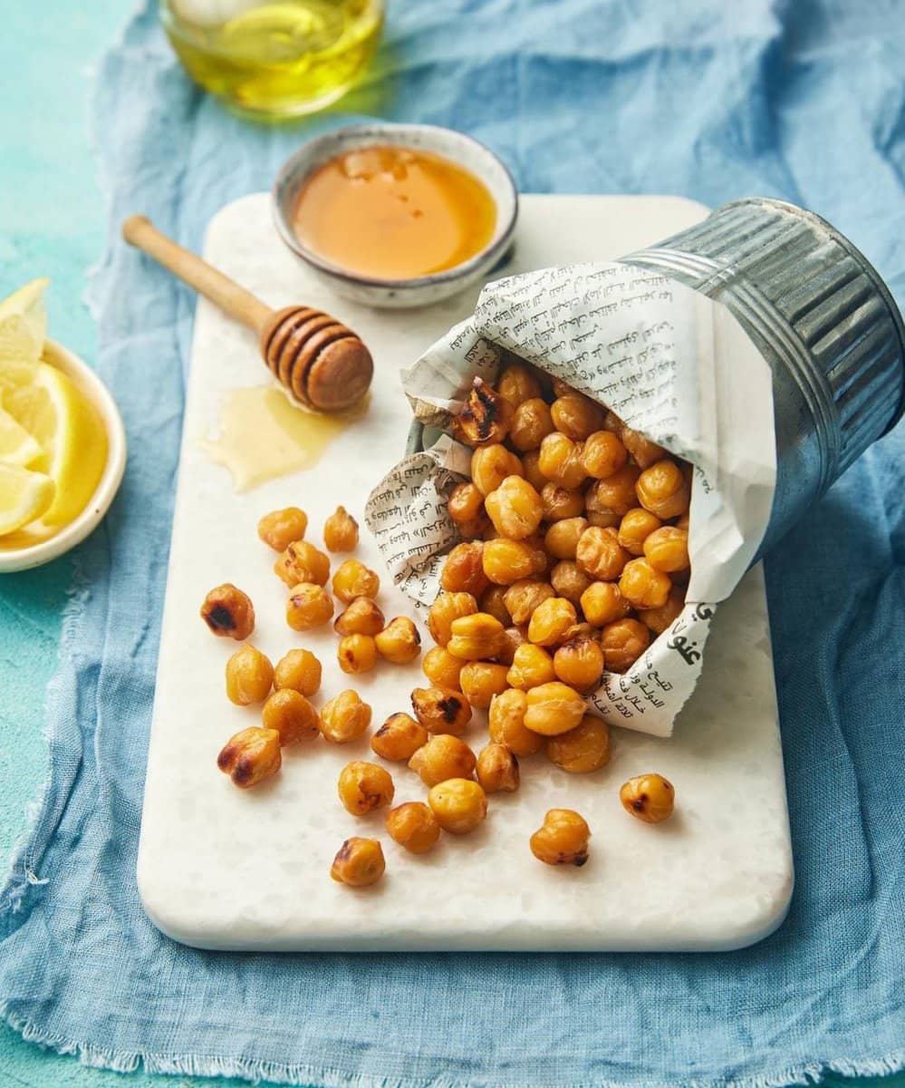 Roasted chickpeas spilling from paper on blue