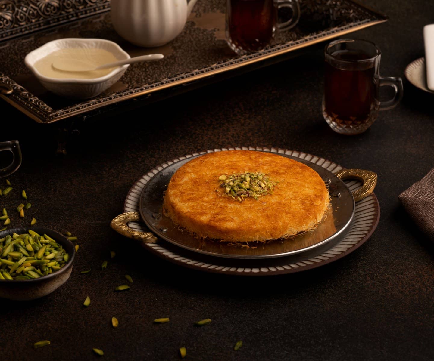 Kunafa in a copper dish on a low-lit table