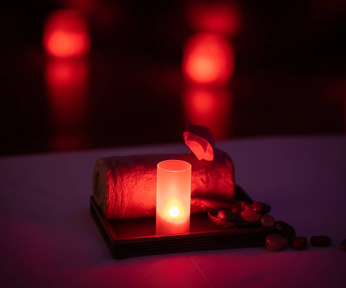 Candle on a spa table in deep red light
