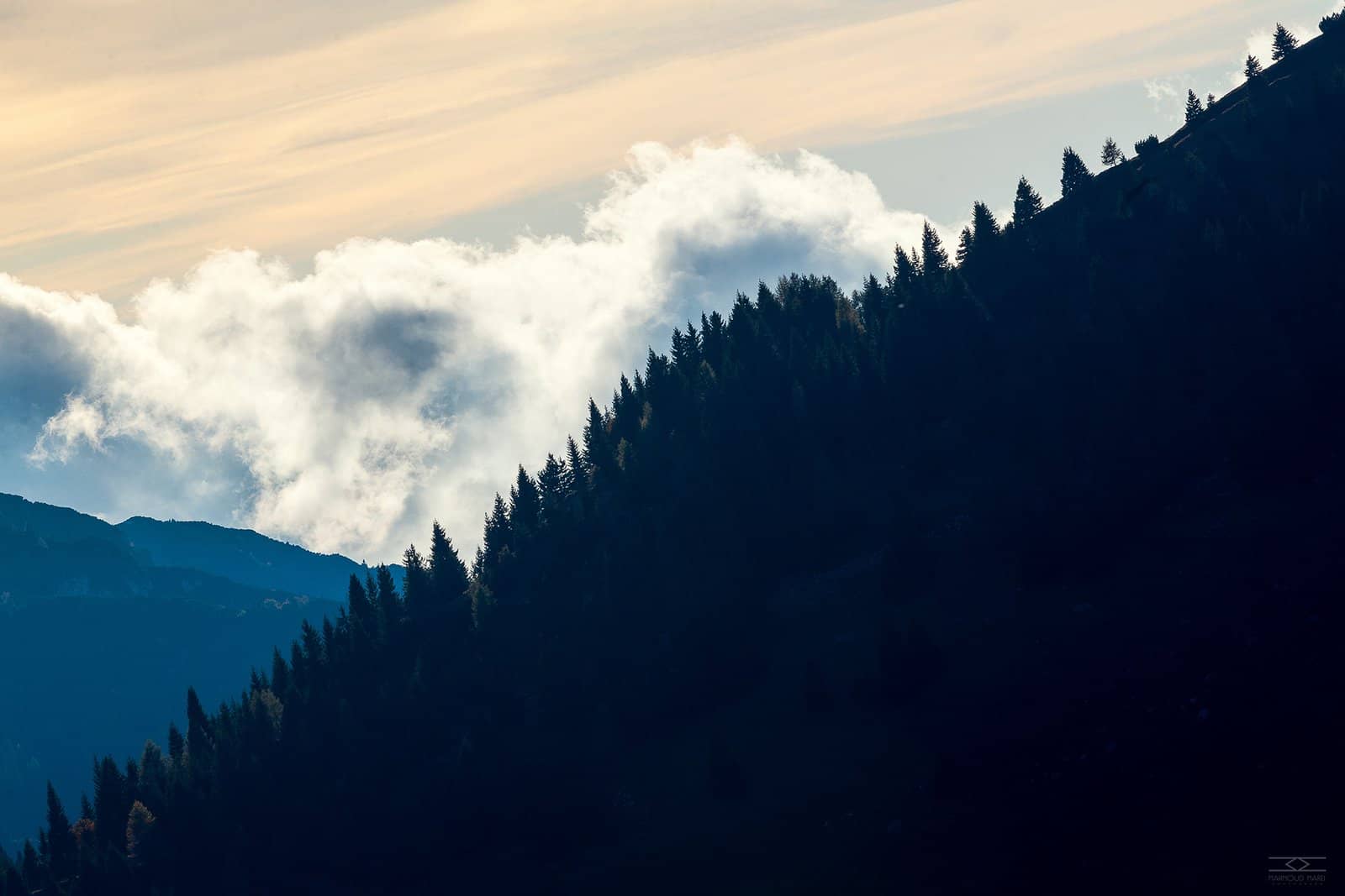 Clouds pouring over a forested ridge in Italy