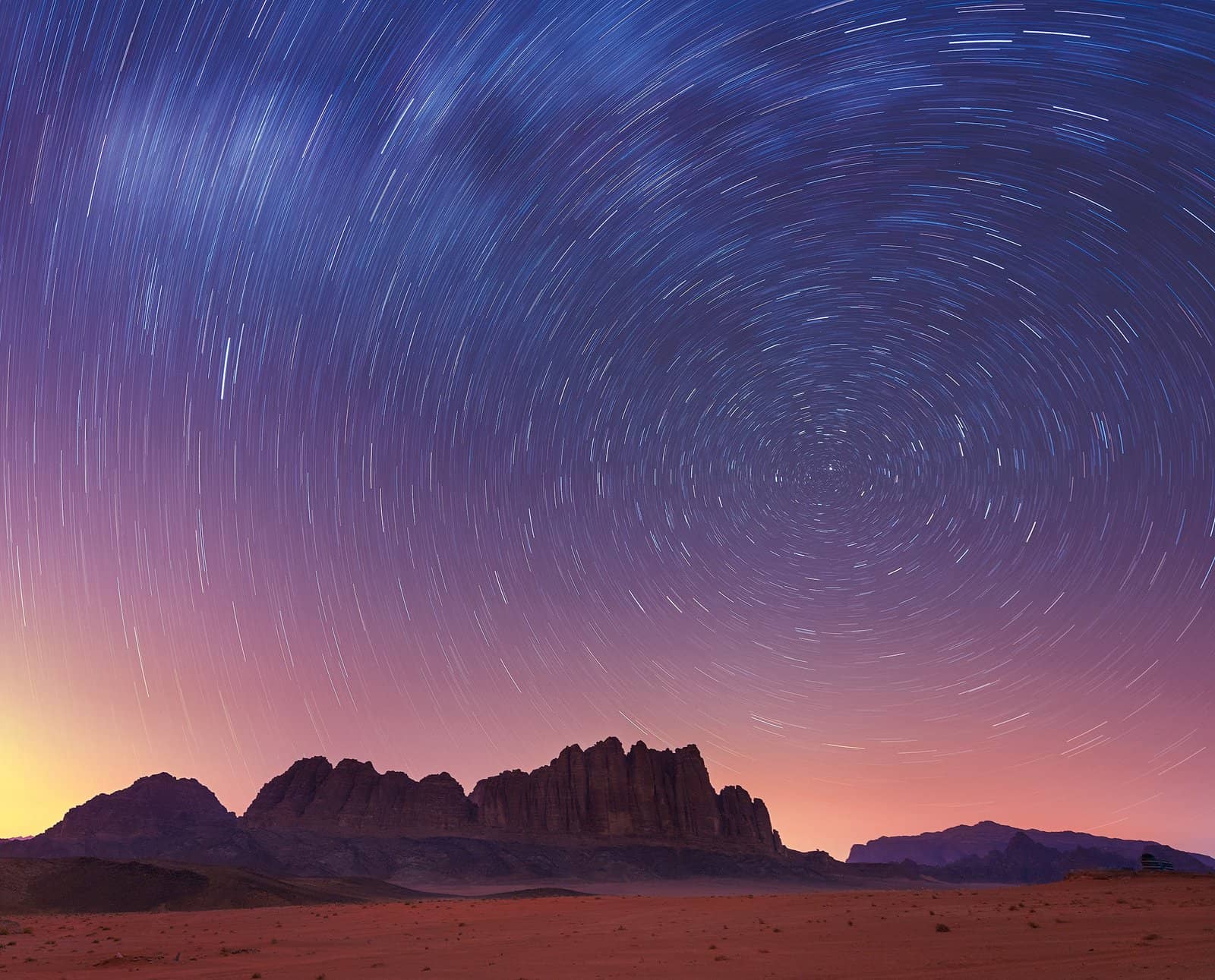 Star trails circling above desert mountains