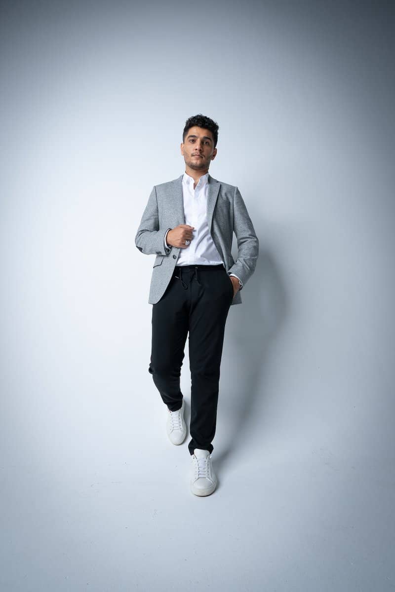 Full-length portrait of a man in a blazer on light grey