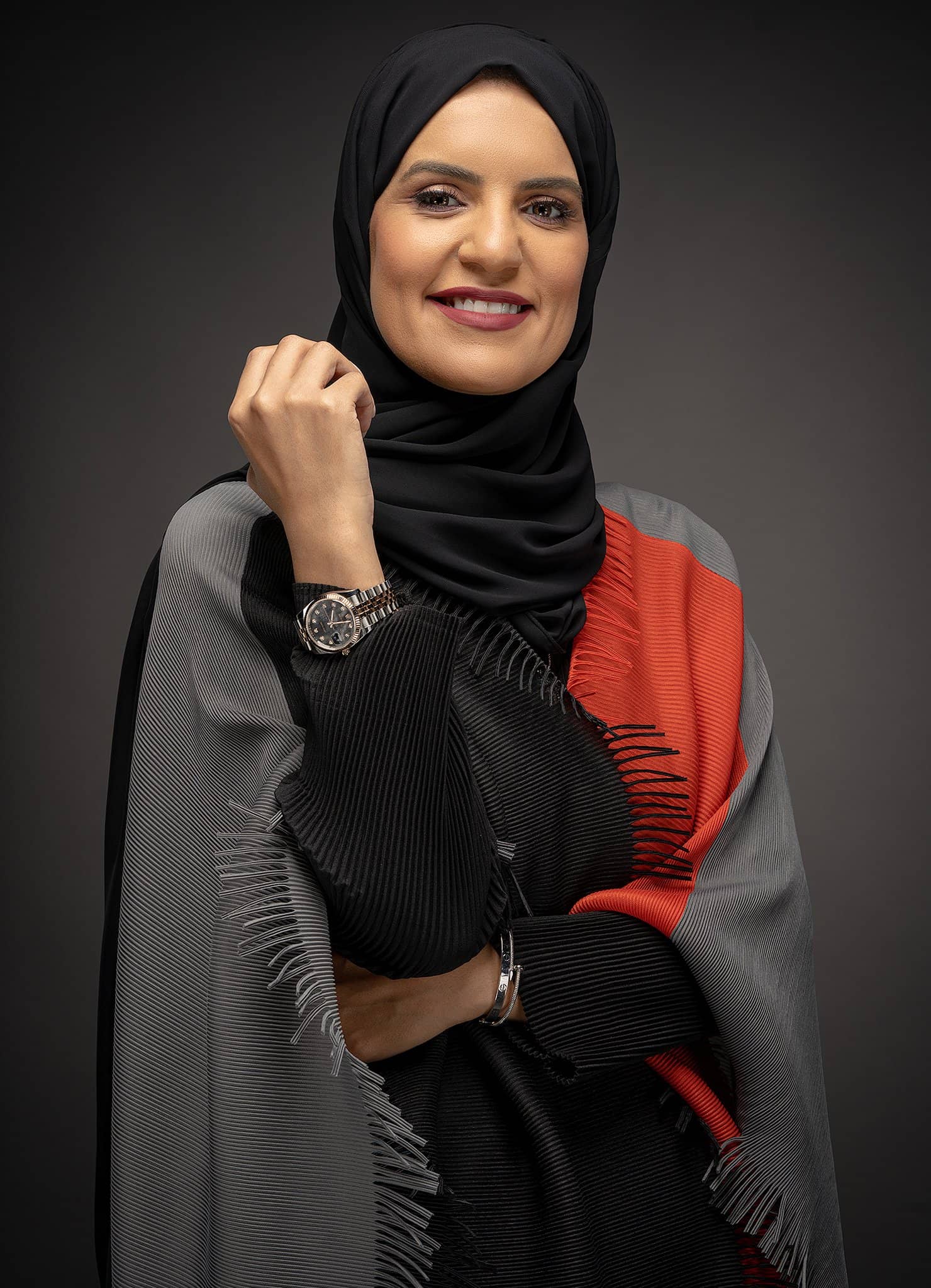 Woman in a black and red abaya, arms folded