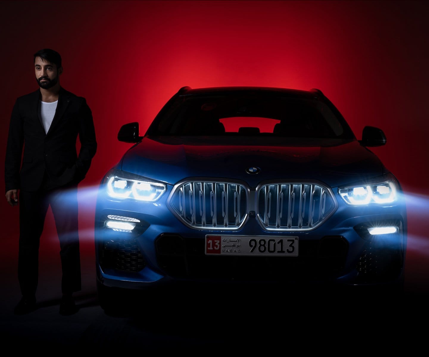 Driver beside a BMW X6 under red studio light