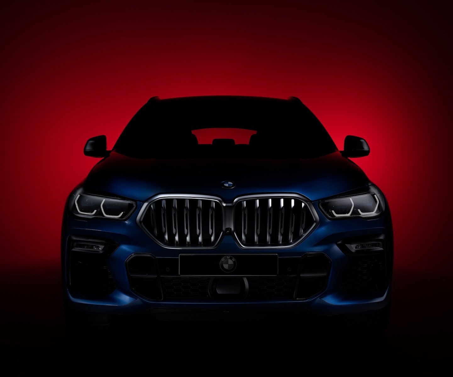 BMW X6 lit in deep red light in the studio