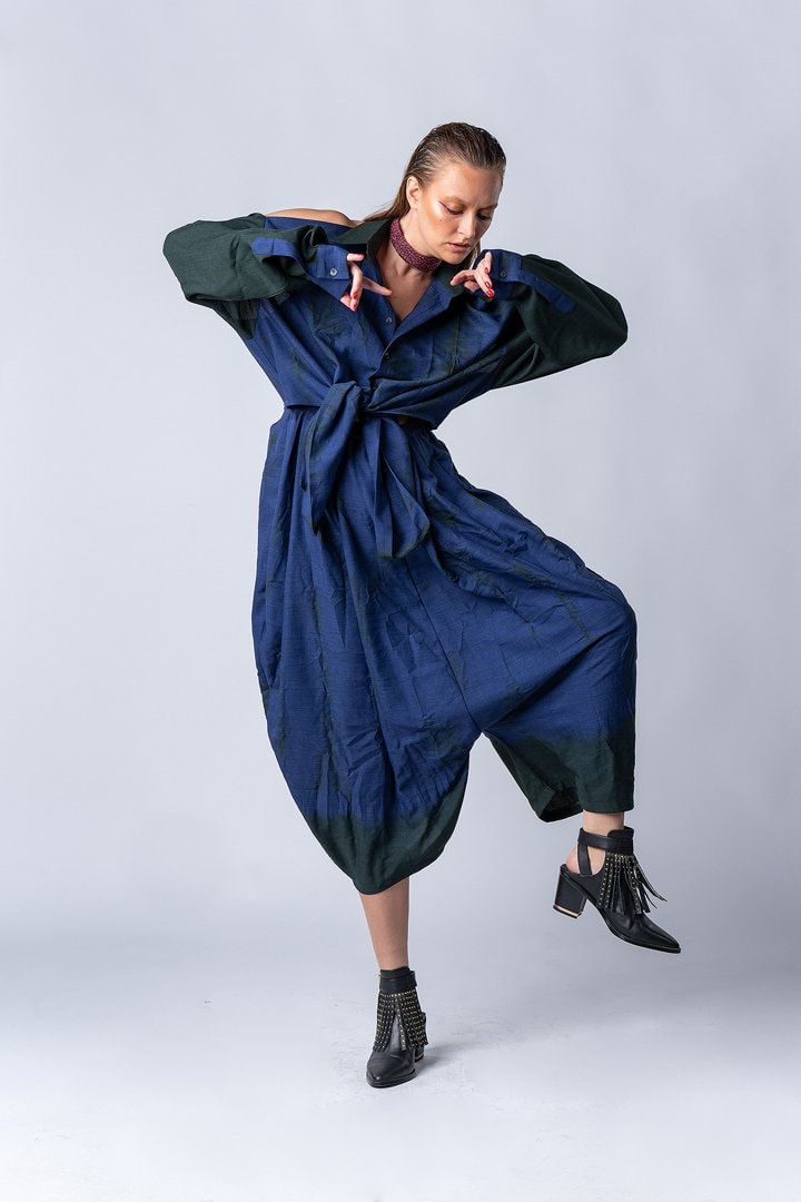 Model in a dark-blue jumpsuit mid-movement on white