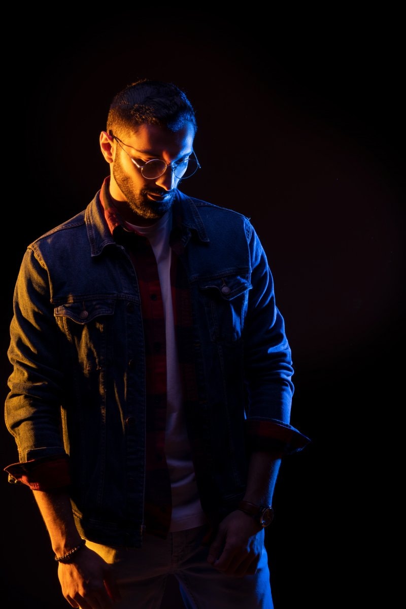 Man in a denim jacket lit with blue and amber gels