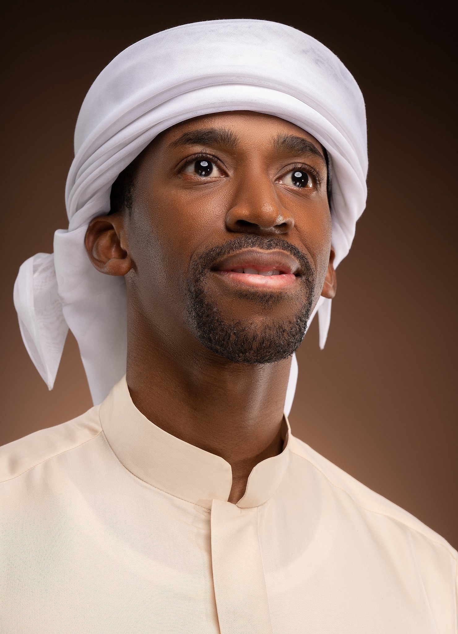 Portrait of a man in a white ghutra on a warm backdrop